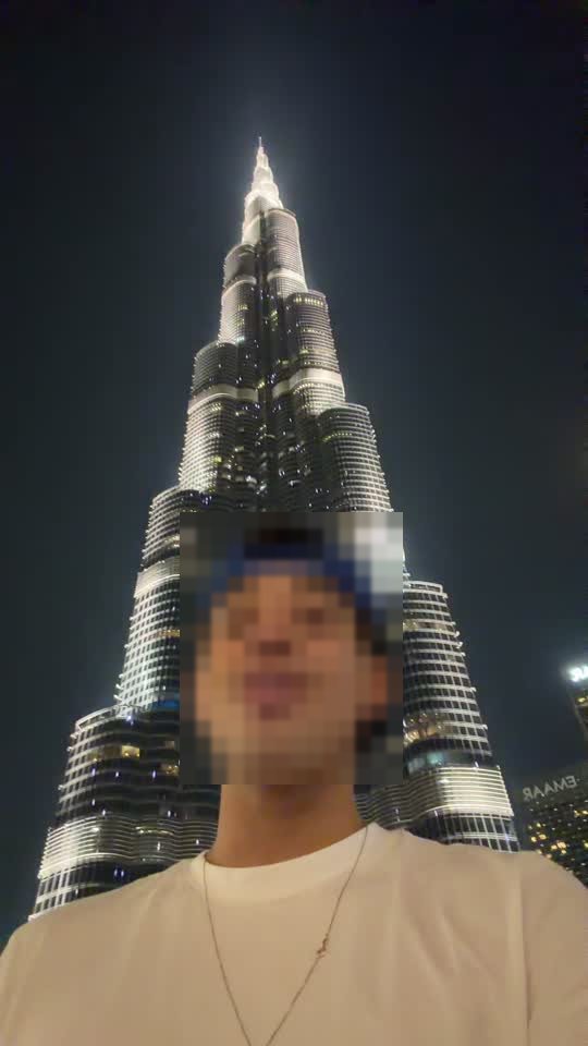 Antes: vídeo real de uma pessoa fazendo selfie em frente a um prédio iluminado, com o rosto desfocado